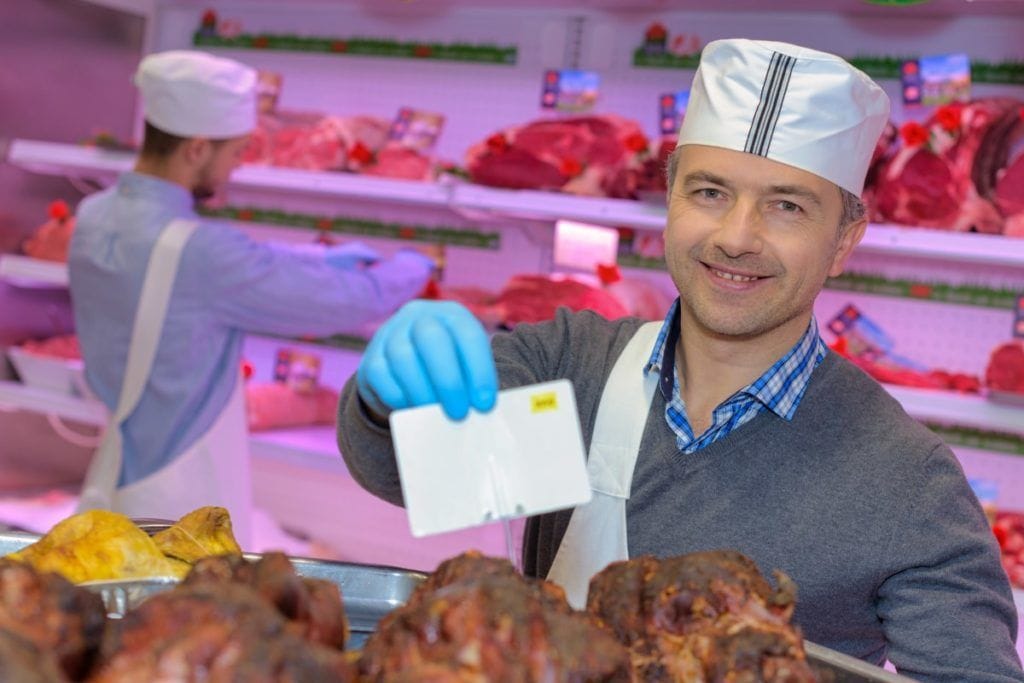 butcher teaching a young one how to sell meat