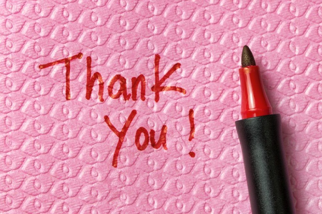 Picture of a Thank you word written on napkin with red pen
